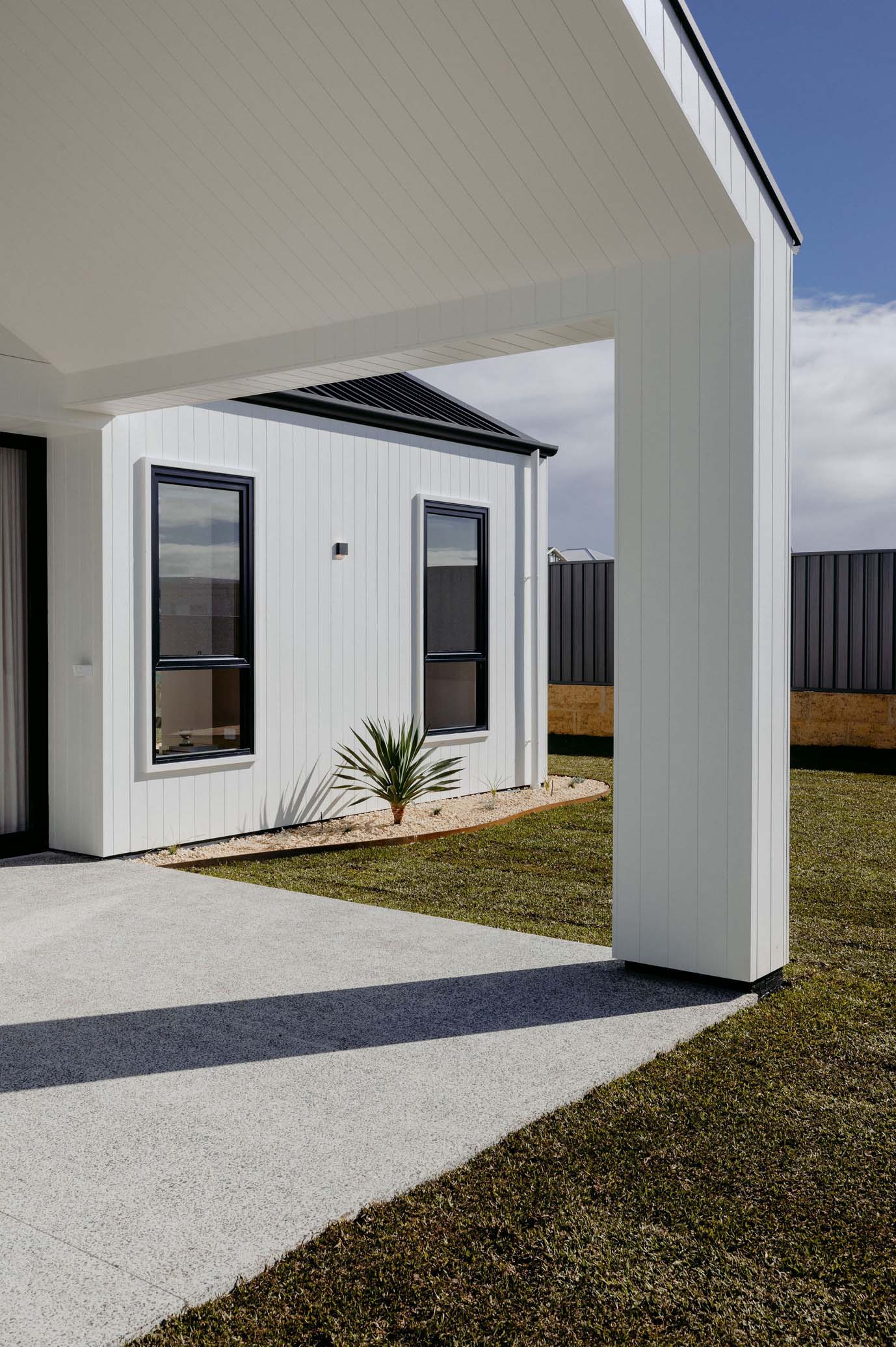 Modern custom home exterior with white vertical cladding, black-framed windows, and covered alfresco area in South West Western Australia